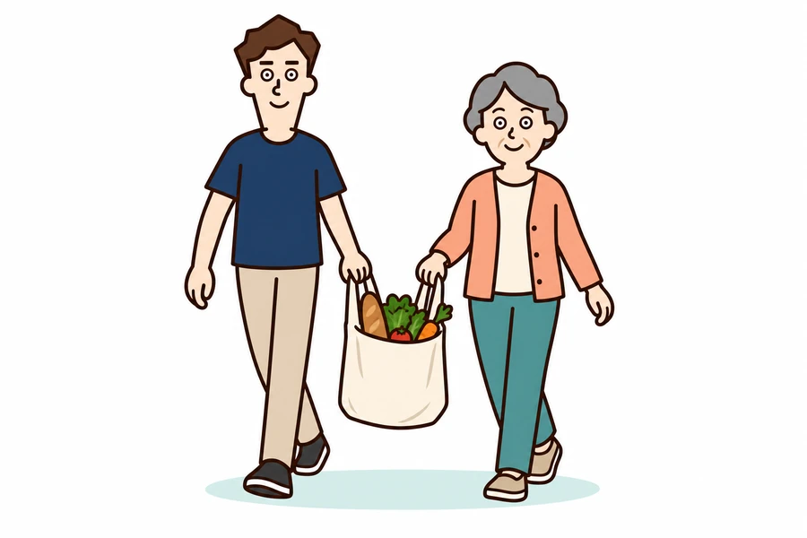利用者と一緒に買い物袋を持って歩く男性スタッフ